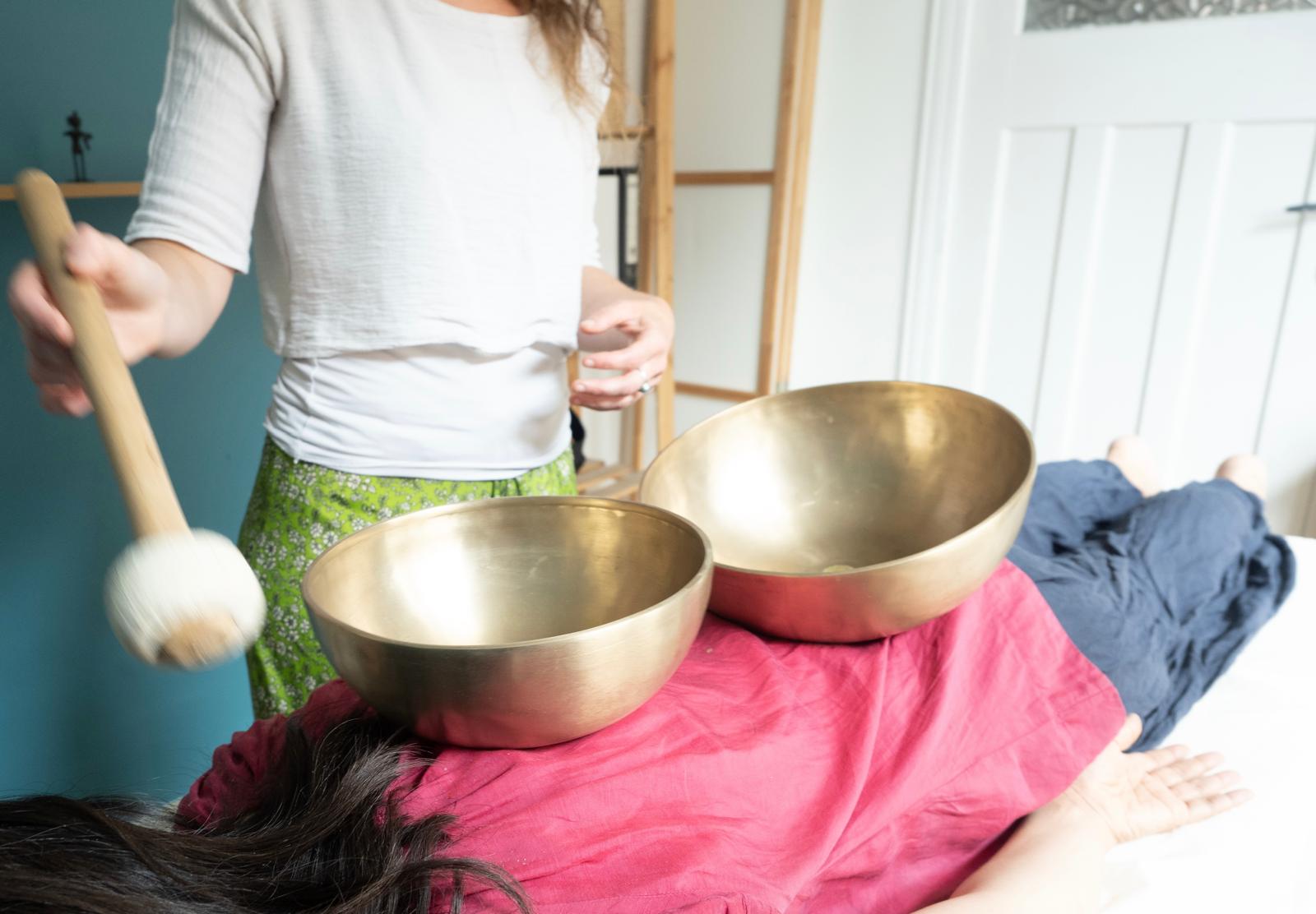 Soin sonore : bols chantants posés sur le corps d'une personne allongée